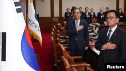 Acting South Korean President and Prime Minister Han Duck-soo salutes to a national flag during a cabinet meeting at the government complex in Seoul, Dec. 14, 2024. (Yonhap via Reuters)