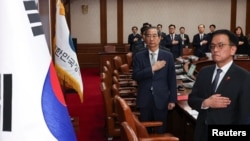 Acting South Korean President and Prime Minister Han Duck-soo salutes to a national flag during a cabinet meeting at the government complex in Seoul, Dec. 14, 2024. (Yonhap via Reuters)