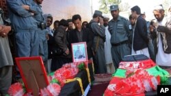  Afghan men stand over the coffins of two police officers killed in a roadside bombing in Ghazni province on April 28, 2013.