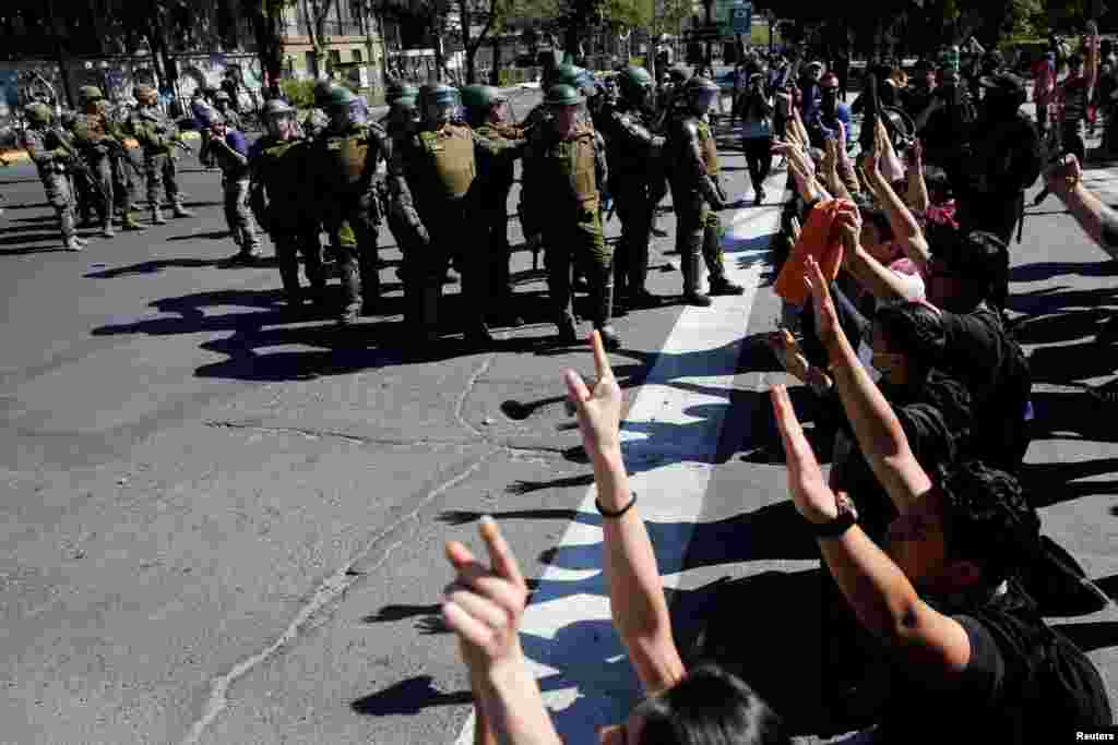 Los manifestantes de rodillas frente a los policías que hacen guardia en la calle durante una protesta contra el modelo económico estatal de Chile en Santiago el 21 de octubre de 2019. REUTERS / Edgard Garrido.