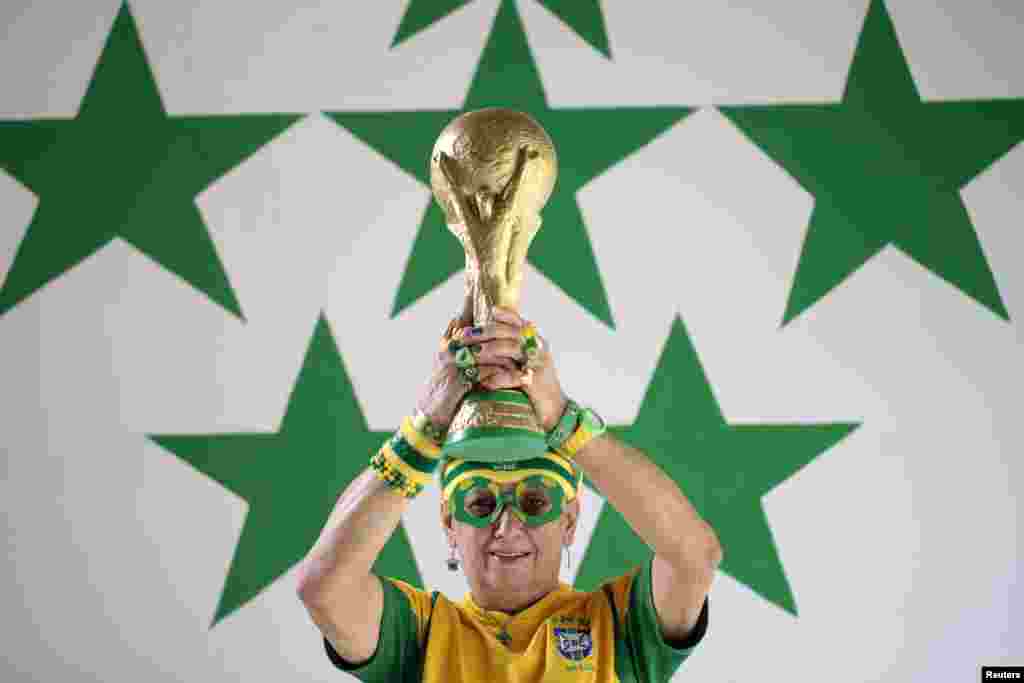 A fã de futebol e acima de tudo fanática pela selecção brasileira, Marilza Guimarães da Silva, de 63 anos, posa para a foto com uma réplica do troféu do Mundial de Futebol, vestida numa das suas diversas indumentárias com as cores do Brasil. Brasília, Maio 27, 2014. REUTERS/Joedson Alves&nbsp;