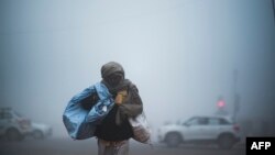 Seorang pria menyeberang jalan saat ibu kota India, New Delhi, berselimut asap tebal akibat suhu udara yang rendah, 30 Desember 2019.