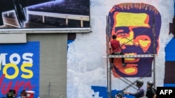 Un hombre pinta un mural del rostro del presidente Nicolás Maduro en una autopista en Caracas, el 5 de junio de 2024. 