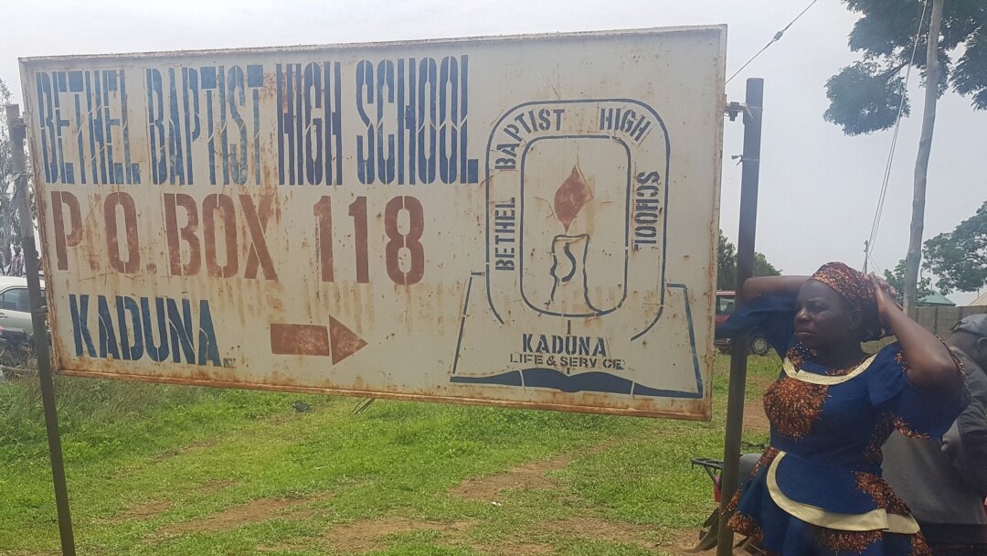 FILE - Parents stand beside a signpost of Bethel Baptist school, where boarding students were kidnapped by bandits in Kaduna, northwestern Nigeria, on July 5, 2021.