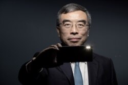 FILE - Chinese CEO of Huawei Liang Hua poses with a Huawei smartphone during a photo session in Paris, Dec. 16, 2019.