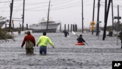 People wade and paddle down a flooded street as Hurricane Sandy approaches, Monday, Oct. 29, 2012, in Lindenhurst, N.Y