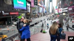 A couple kisses as they pose for a photo at the top of the TKTS stairs, March 10, 2020, in New York's Times Square.