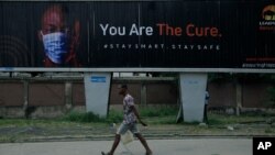 A man walk past an electronic billboard warning residents to wear face masks to protect against coronavirus, in Lagos Nigeria, Sept. 1, 2020.
