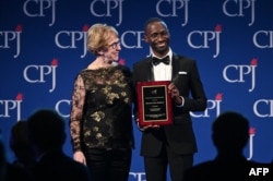 FILE - Sandra Mims Rowe, left, and Maxence Melo Mubyazi pose on stage at the Committee to Protect Journalists' 29th Annual International Press Freedom Awards, Nov. 21, 2019, in New York.