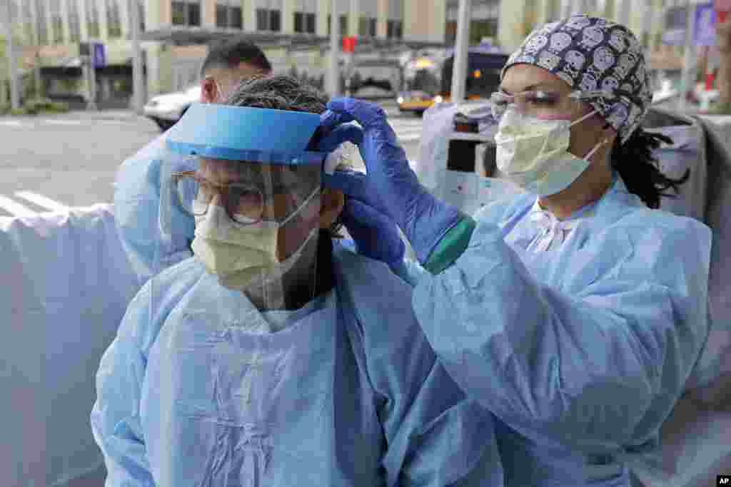 یک پرستار سرویس عاجل مرکز طبی هابرویو در شهر سیاتل ایالت واشنگتن یک همکاراش را در پوشیدن ماسک طبی کمک می&zwnj;کند.