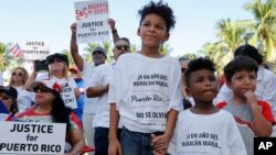 Hector Rivera, 8, Mario Jordan Micael, 3, and Ramon Montes, 5, participate in a rally in West Palm Beach, Fla., Sept. 22, 2018, marking the one-year anniversary of Hurricane Maria's devastation of Puerto Rico.
