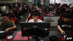 FILE - People play computer games at an internet cafe in Beijing on September 10, 2021. China recently announced new plans to restrict the online gaming industry, sending shares in tech giants including Tencent tumbling. (Photo by GREG BAKER / AFP)