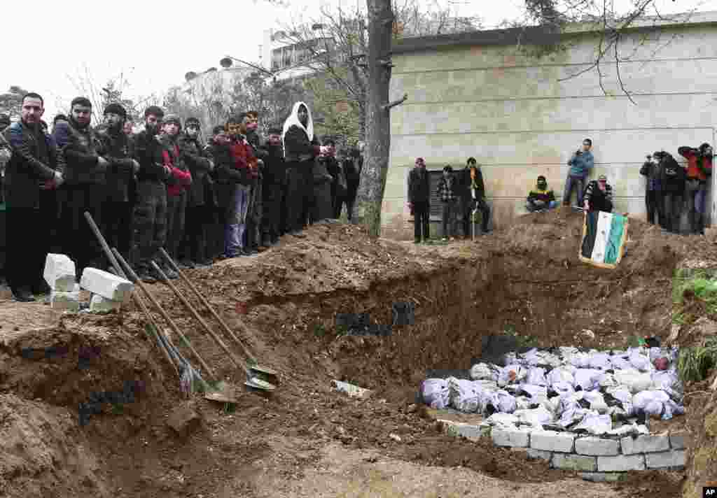 Syrian citizens pray over the bodies of those who were found dead next to a river last Tuesday and who were not identified by their relatives, in Aleppo, Syria on January 31, 2013.