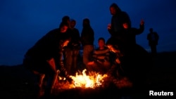 Turkish Kurds sit around a fire to warm themselves as they watch the Syrian town of Kobani from a hill near the Mursitpinar border crossing, on the Turkish-Syrian border in the southeastern town of Suruc, Turkey, Oct. 22, 2014.