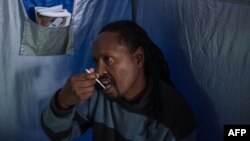 FILE: Forty-five year-old Oscar Tyumre uses an HIV self-testing kit, administered by students from the University of the Witwatersrand in Hillbrow, Johannesburg, on March 19, 2018. Self-testing kits and vending machines distributing prescription drugs are two ways that