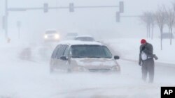 Seorang pria menelepon untuk menunggu bantuan setelah mobilnya terjebak dalam badai salju di kota Lawrence, Kansas hari Minggu (24/11). 