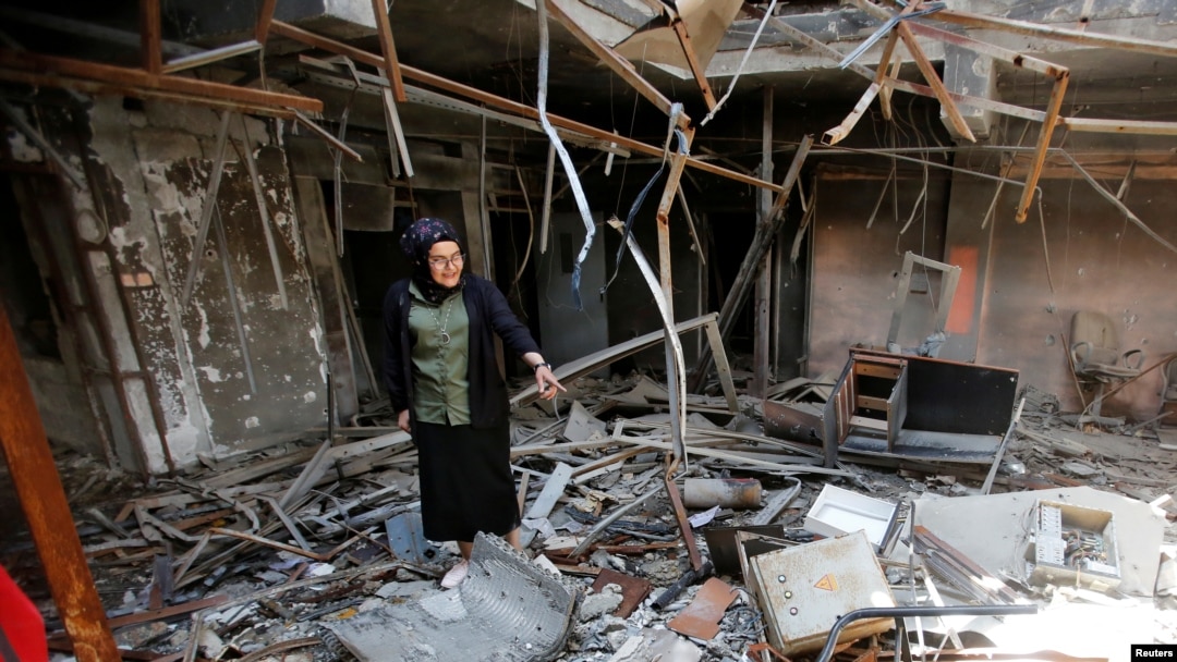 FILE - Raghad Hammoudi, a member of a group of students campaigning to help rebuild the Central Library of Mosul University, stands amid rubble in Mosul, Iraq, May 14, 2018. 