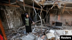 FILE - Raghad Hammoudi, a member of a group of students campaigning to help rebuild the Central Library of Mosul University, stands amid rubble in Mosul, Iraq, May 14, 2018. 