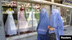 Mujeres afganas caminan frente a una tienda especializada en vestidos de boda en Kabul.