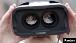 FILE - A girl wears a virtual reality headset outside the Great Hall of the People in Beijing after the opening session of the Chinese People's Political Consultative Conference in Beijing, China, March 3, 2016. 