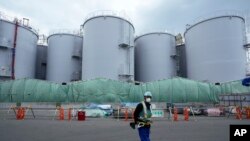 ARSIP - Seorang pekerja berdiri di dekat tangki yang digunakan untuk menyimpan air radioaktif di pembangkit listrik tenaga nuklir Fukushima Daiichi, di Okuma kota, timur laut Jepang, Kamis, 3 Maret 2022. (AP/Hiro Komae, File)