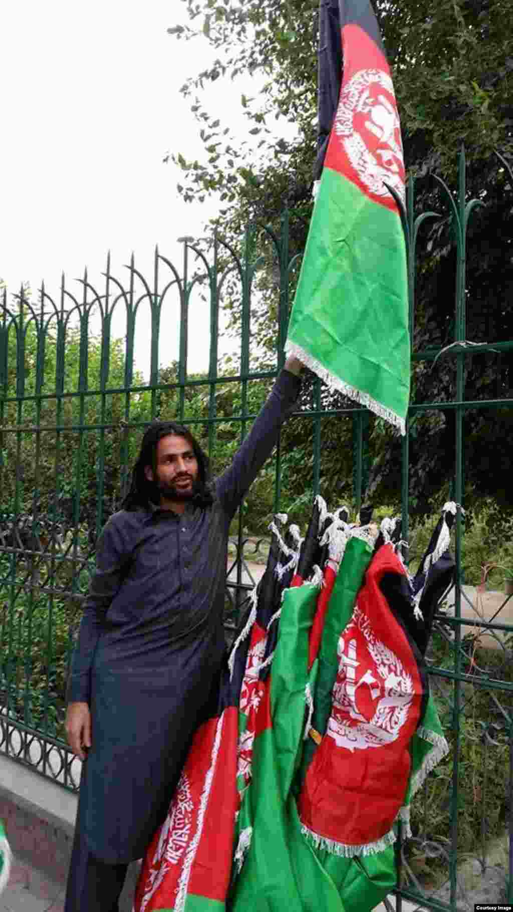 این جوان به افتخار از سالگرد استقلال افغانستان بیرق های ملی را با خود حمل مینماید