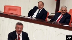 Prime Minister Binali Yildirim, rear right, smiles as he listens to opposition lawmaker Engin Altay before a parliamentary vote in Ankara, Turkey, Sept. 23, 2017. The Turkish parliament renewed a bill allowing the military to intervene in Iraq and Syria if faced with national security threats — a move seen as a final warning to Iraqi Kurds to call off their Monday independence referendum.