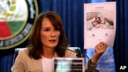 Georgette Gagnon, the director of human rights for the U.N. mission in Afghanistan holds up a copy of a UN report during a news conference in Kabul, Afghanistan, July 9, 2014. 