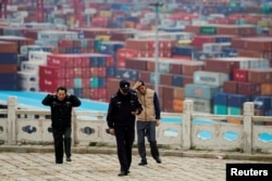Security guards walk in front of containers at the Yangshan Deep Water Port in Shanghai, China, April 24, 2018.
