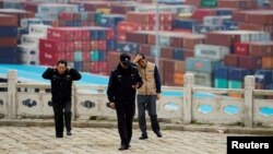 FILE - Security guards walk in front of containers at the Yangshan Deep Water Port in Shanghai, China, April 24, 2018.