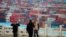 FILE - Security guards walk in front of containers at the Yangshan Deep Water Port in Shanghai, China, April 24, 2018. The U.S. will impose tariffs Friday on $34 billion worth of Chinese imports.