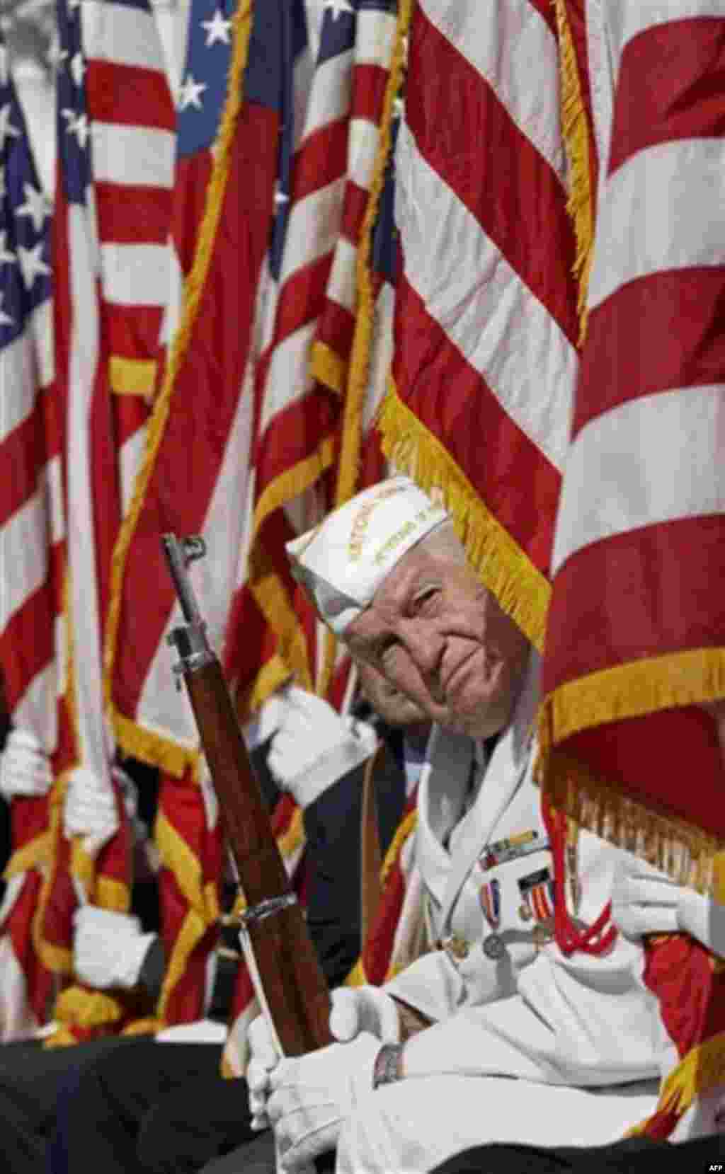A member of the National Honor Guard looks out from behind an American flag to listen to President Barack Obama as he speaks during a Veteran�s Day ceremony at Arlington National Cemetery in Arlington, Va., Friday, Nov. 11, 2011. (AP Photo/Pablo Martinez
