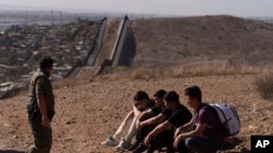 El agente de la Patrulla Fronteriza Gutiérrez camina junto a cuatro hombres detenidos después de cruzar la frontera ilegalmente por un espacio entre dos muros que separan a México de Estados Unidos. [Foto:Archivo/AP]