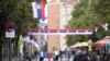 FILE - People walk through a street decorated with Serbian flags in Mitrovica, Kosovo, Oct. 5, 2019.