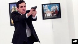 A gunman gestures after shooting the Russian Ambassador to Turkey, Andrei Karlov, at a photo gallery in Ankara, Turkey, Dec. 19, 2016.