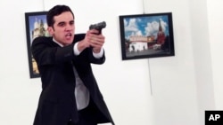 A gunman gestures after shooting the Russian Ambassador to Turkey, Andrei Karlov, at a photo gallery in Ankara, Turkey, Dec. 19, 2016.