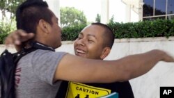 Students Irvis Orozco, left, and Jorge Gutierrez hug outside the US Citizenship and Immigration Services at the Federal Building in Los Angeles Wednesday, Aug. 15, 2012.