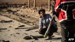 Syrians look for unexploded ammunition at the site of the previous evening's Israeli airstrike that targeted shipments of weapons that belonged to Syrian government forces in Qamishli, in mainly Kurdish northeastern Syria, on December 10, 2024.