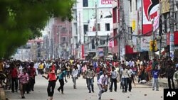 Bangladeshi garment workers throw objects towards policemen during clashes in Dhaka, 30 Jun 2010