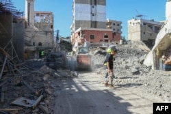 Layanan darurat membersihkan puing-puing bangunan yang hancur akibat serangan Israel di Tyre, Lebanon selatan, 23 Oktober 2024. (KAWNAT HAJU / AFP)