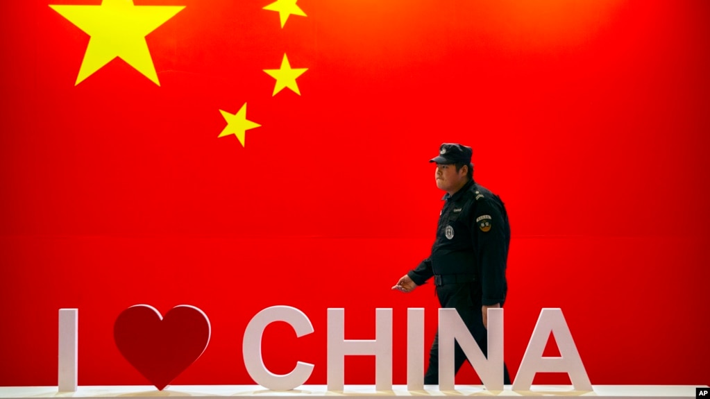 资料照:一名保安人员在北京举行的信息通信展览会上走过“我爱中国”的标语。(2019年10月31日)