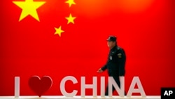 资料照：一名保安人员在北京举行的信息通信展览会上走过“我爱中国”的标语。（2019年10月31日）
