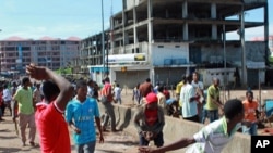 Peul youths throw stones toward members of the Malinke ethnic group, during clashes between Malinke and Peul shopkeepers in Conakry, Guinea, Sept. 21, 2012. 