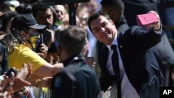 FILE - Brazil's Senator Flavio Bolsonaro takes selfies with supporters of his father, President Jair Bolsonaro, during the Independence Day celebrations in Brasilia, Brazil, Sept. 7, 2020. 