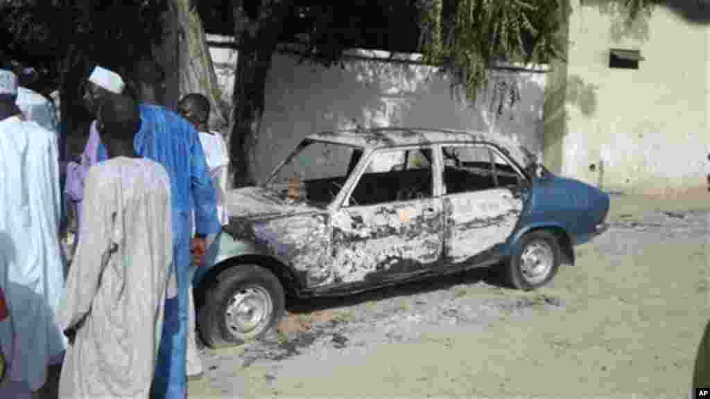 Men stand by a burnt car following an attacked by Boko Haram in Benisheik.