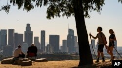 FILE - In this Monday, Jan. 11, 2021, file photo, people overlook the skyline of Los Angeles. California is losing a U.S. House seat for the first time, dropping its delegation from 53 to 52 members.