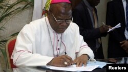 Congolese Archbishop Fridolin Ambongo, one of the Roman Catholic bishops mediating the talks, signs the accord between the opposition and the government of President Joseph Kabila at the ConfŽrence Žpiscopale nationale du Congo (CENCO) headquarters in Gombe Municipality, in the Congolese capital Kinshasa, December 31, 2016. 