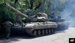 FILE - Pro-Russian troops prepare to travel in a tank on a road near the town of Yanakiyevo, Donetsk region, eastern Ukraine, June 20, 2014.