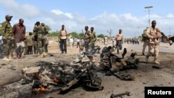 Somali government forces assess the scene of a suicide car explosion in Hodan district in the capital Mogadishu, June 24, 2015. 