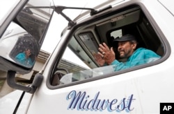 Charles McCaskill, a trucker heading to Nebraska to deliver frozen salmon, talks from the cab of his truck while parked while waiting for Interstate 90 to reopen, Jan. 18, 2017, in North Bend, Wash.